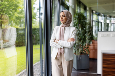 Muslim woman standing in office and looking outside